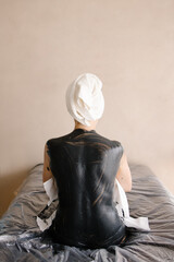 Whole body mud wrap is covered with clay mask. Spa procedure in a luxury salon. Black clay...