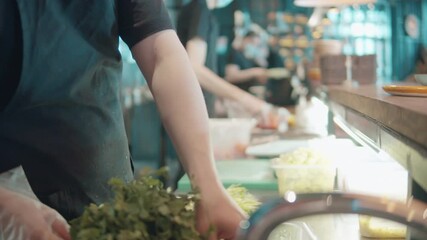 A cook is tearing off parsley behind the restaurant counter