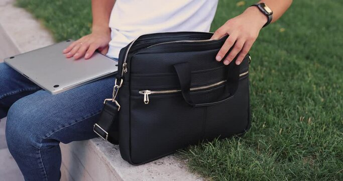 Unrecognizable man puts a laptop into the bag
