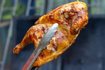 Half Of A Jerk Chicken being held with Tongs