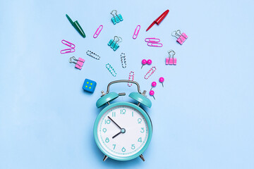Alarm clock and stationery set on blue pastel background. Back to school concept.