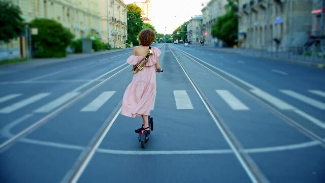 a woman riding in a summer dress in the middle of an empty road dances, behind her back a trumpet . the image of a creative and courageous person.