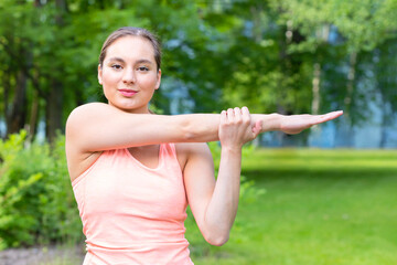 closeup portrait fitness trainer woman warm up, stretching hands, workout in park outdoors. sportive girl doing yoga exercises in park. sports in city. female healthy sport lifestyle.
