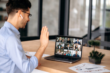 Fototapeta premium Caucasian successful businessman having virtual online meeting with diverse people, talking with multiracial colleagues via video conference call using laptop, sits in office, greeting interlocutors