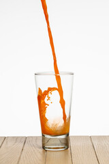 Glass with carrot juice on table on white background