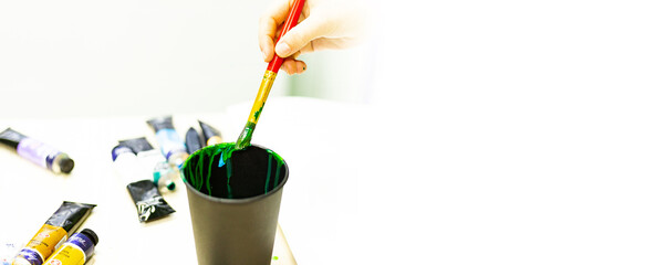the artist's hand washes a brush with paints in a glass of water, an artist's tool, creativity, drawing, drawing training, art school, banner