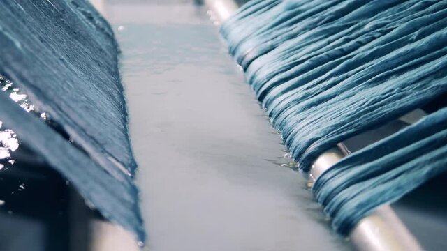 Textile production, clothes manufacturing concept. Strips of yarn are getting washed after colouring