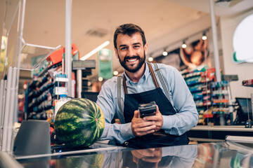 Portrait of handsome smiling male cashier working at a grocery store.