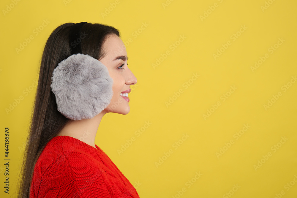 Canvas Prints Beautiful young woman wearing earmuffs on yellow background. Space for text