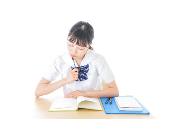 机で勉強をする制服姿の女子学生
