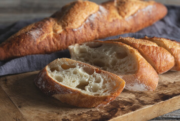 A sliced baguette on an old wooden cutting board.