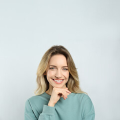 Portrait of happy young woman with beautiful blonde hair and charming smile on light background