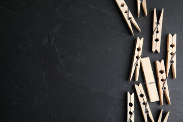 Wooden clothespins on black slate table, flat lay. Space for text