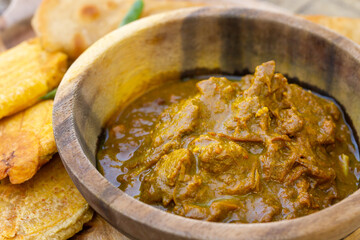 An overhead shot of some delicious Jamaican Curry Goat taken in a wooden bowl.