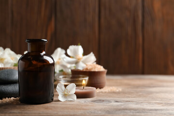 Beautiful composition with jasmine essential oil and fresh flowers on wooden table. Space for text