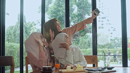 Pretty muslim woman and lovely friend selfie in coffee shop