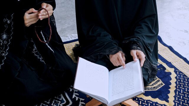 Young muslim woman and sister while read quran praying