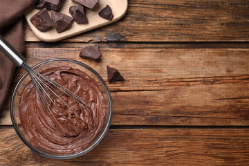 Chocolate cream with balloon whisk on wooden table, flat lay. Space for text