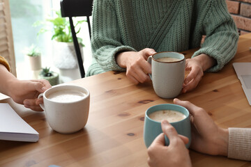 Women with cups of coffee at table in cafe, closeup