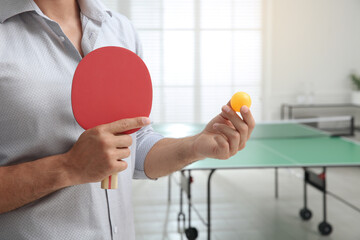 Businessman with tennis racket and ball near ping pong table in office, closeup