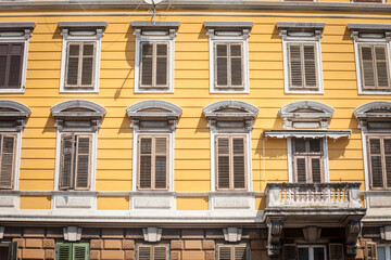 Typical italian mediterranean facade of a residential building, yellow, with traditional European wooden blinds and a balcony, on a vintage old house, in istria region, by the adriatic...
