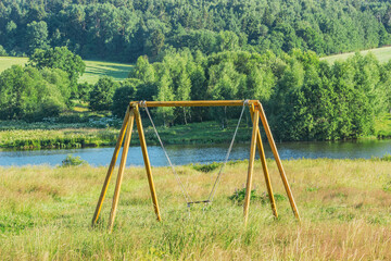 Wooden swing on the countryside background.