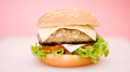 Classic cheeseburger with beef patty,  cheese, tomato, onion, lettuce and ketchup isolated on pink background, food preparation, fast food concept.