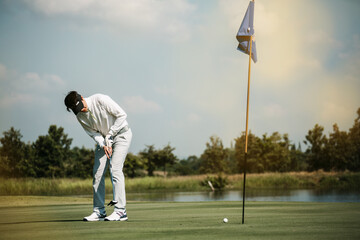 Obraz premium Golfers putting golf balls on the green amid the warm sunshine in the morning. Concept of Outdoor activities and Outdoor sports, Concept of Golfer and Lifestyle.