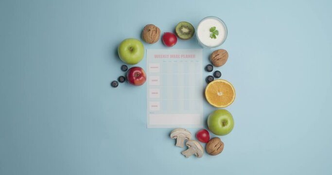 Blank meal plan and different products on color background, video with stop motion effect