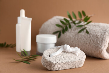 Obraz na płótnie Canvas Pumice stone, cosmetic products and towel on brown background