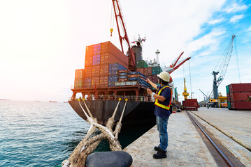 Engineers and crane.smiling dock worker holding radio and ship background