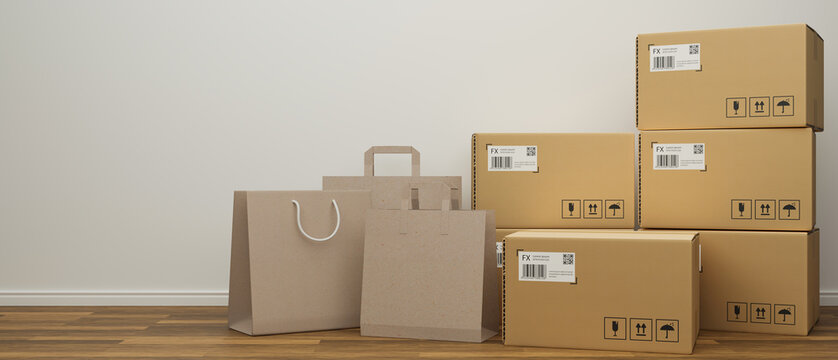 Shopping bags and cardboard boxes stacked on the wooden floor with white wall background