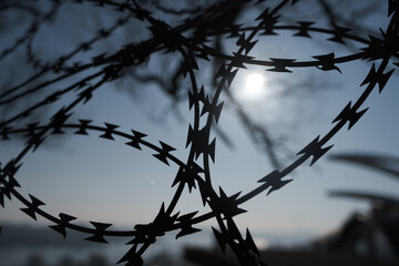 Barbed wire on the background of the blurred sun.