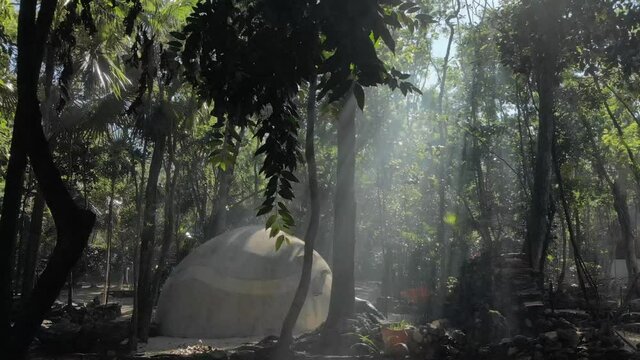 view of temazcal (sweating lodge) in the jungle with ray of light