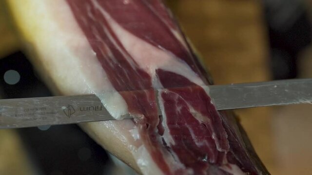 Close up Tracking shot of Sharp Knife thin slicing Spanish serrano Ham