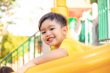 Child playing on the outdoor playground. Kids play in school or kindergarten yard. Active kid on colorful slide and swing. Healthy summer activity for children.