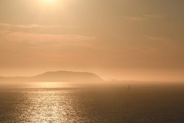 Sailboat in distance in the misty islands at dusk