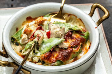 Baked hot spinach crepes roll with chicken, cheese, mushroom and bechamel sauce. Food recipe background. Close up
