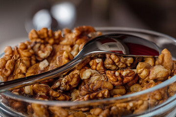 Walnuts in a small glass plate with a spoon.