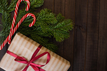 christmas composition: gift, fir branches and lollipops on wooden background