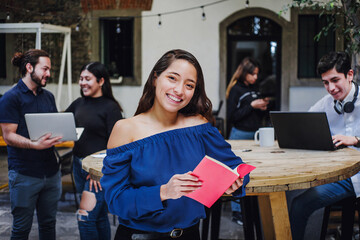 Portrait of young latin student girl holding a book at university in Latin America