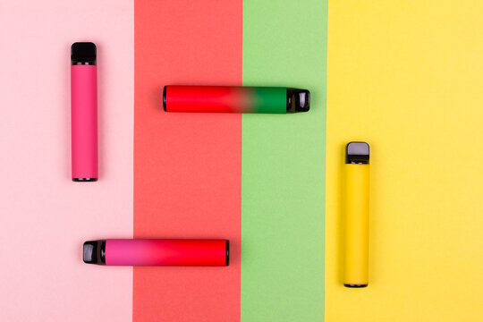 Disposable single pink e-cigarettes with saline nicotine. Pod systems of different colors. Devices for quitting smoking. Red, yellow, green, pink. conceptual fashion photo. Lines and geometry