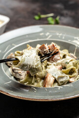 Traditional Italian cuisine, Tagiatelle pasta with creamy sauce with porcini mushrooms and chicken. cooking concept, vertical image. copy space - obrazy, fototapety, plakaty