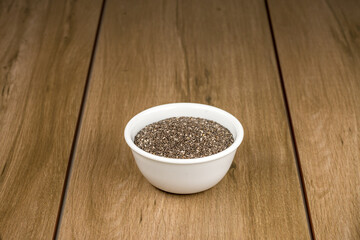 Tazón de cerámica blanca con semilla de chia sobre madera