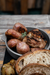 Barbecue. Traditional asado criollo plate. Closeup view of chorizos, pork sausages, grilled sweetbreads, potatoes and bread on the wooden table. 