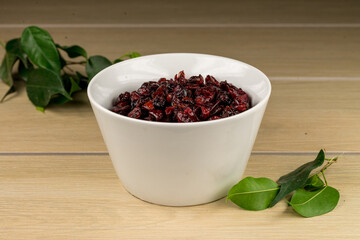 Tazón de cerámica blanca con arándanos secos sobre madera