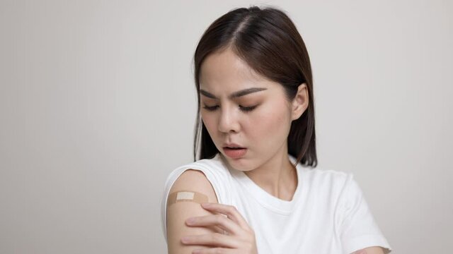 Young beautiful asian woman feel pain in arm after receiving the vaccine. She was worried and stressed that there would be side effects. She tried to massage her aching arm.