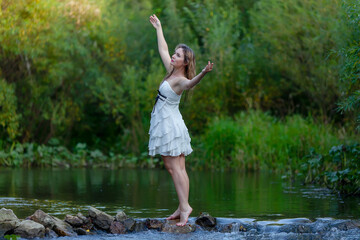 woman in white dress splashes in the river