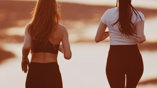 Two young women jogging on sunset evening