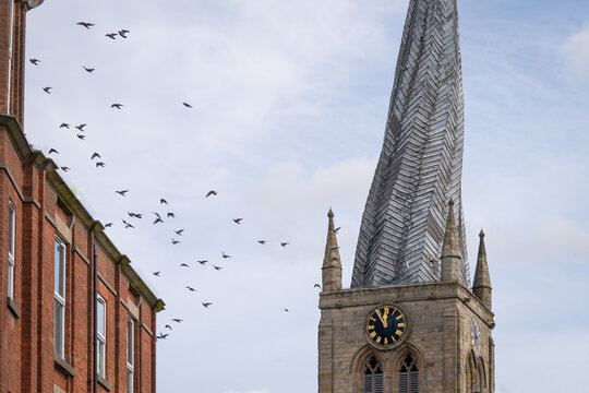 Chesterfield crooked spire church with birds flying in sky. St Marys Church Chesterfield, Derbyshire with twisted steeple spire.